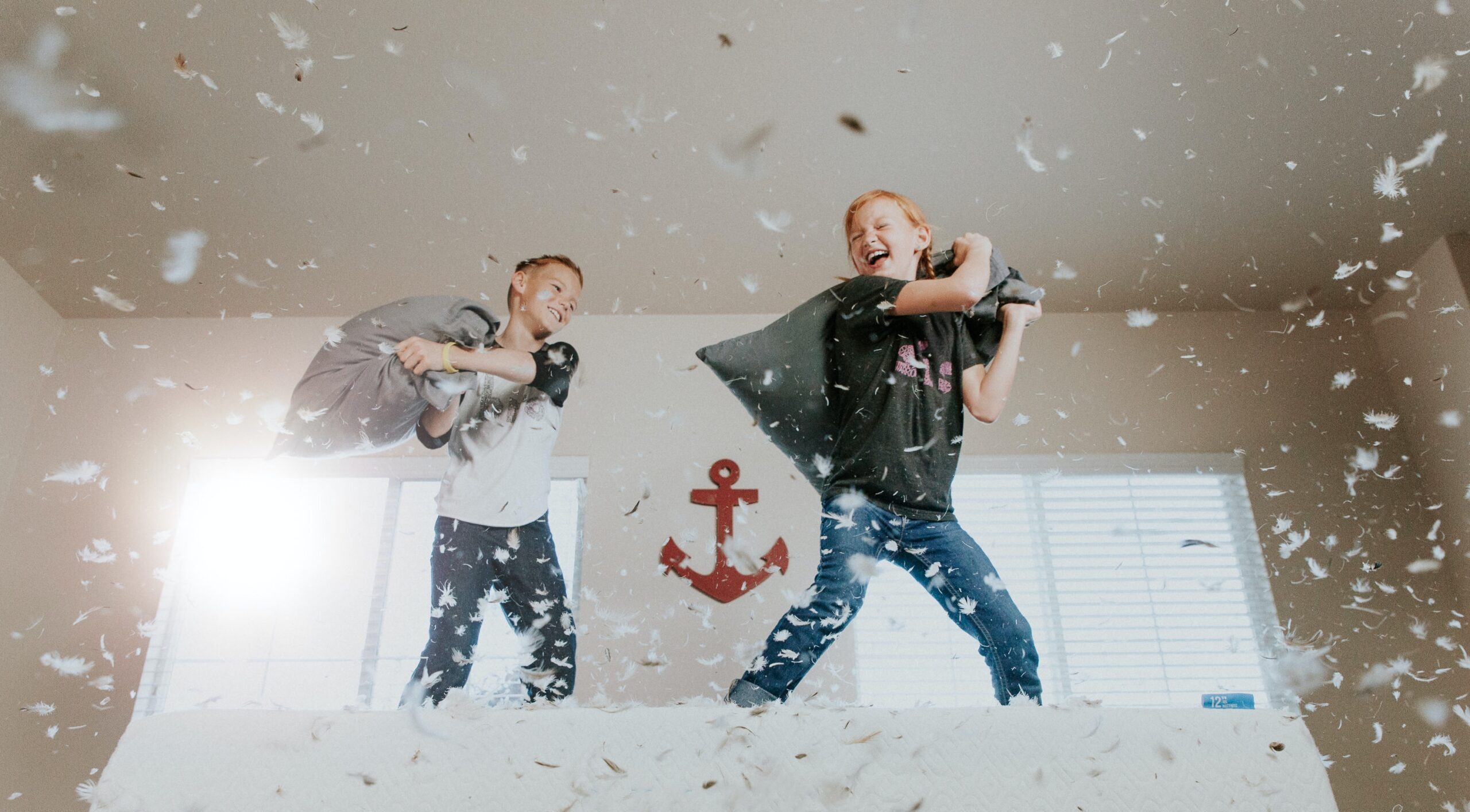 Zwei Kinder spielen mit Schaum im Wohnzimmer, lachen und haben Spaß.
