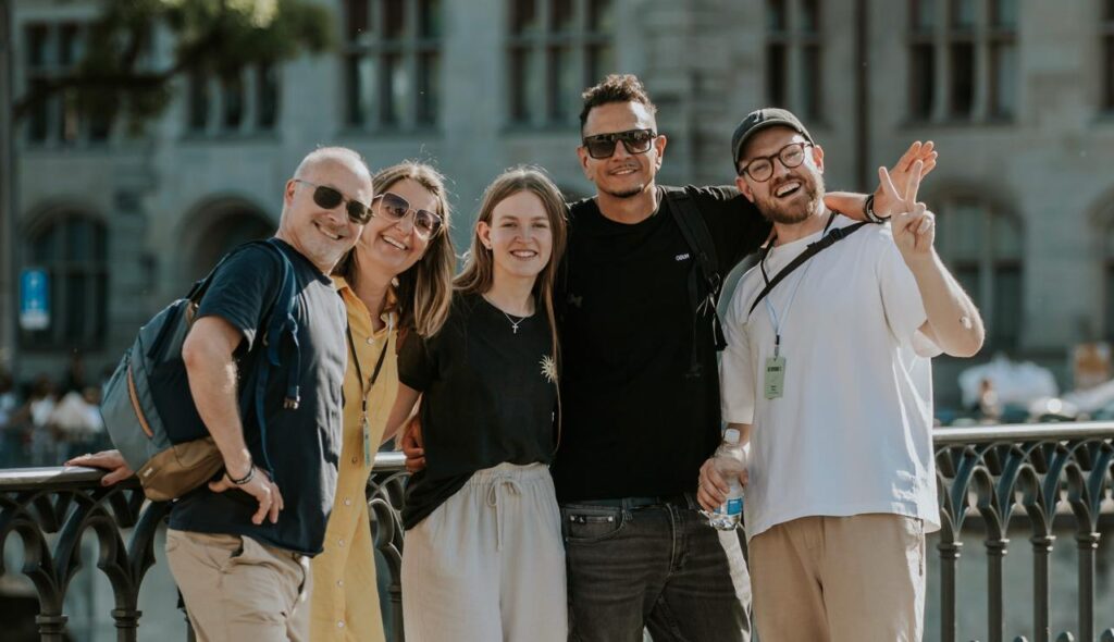 Gruppe junger Menschen beim Sightseeing in Augsburg, lachend und in entspannter Atmosphäre, mit historischen Gebäuden im Hintergrund.