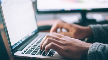 Person tippt auf einer Laptop-Tastatur während eines Online-Gottesdienstes bei ICF Augsburg, symbolisiert digitale Gemeinschaft und christlichen Glauben.