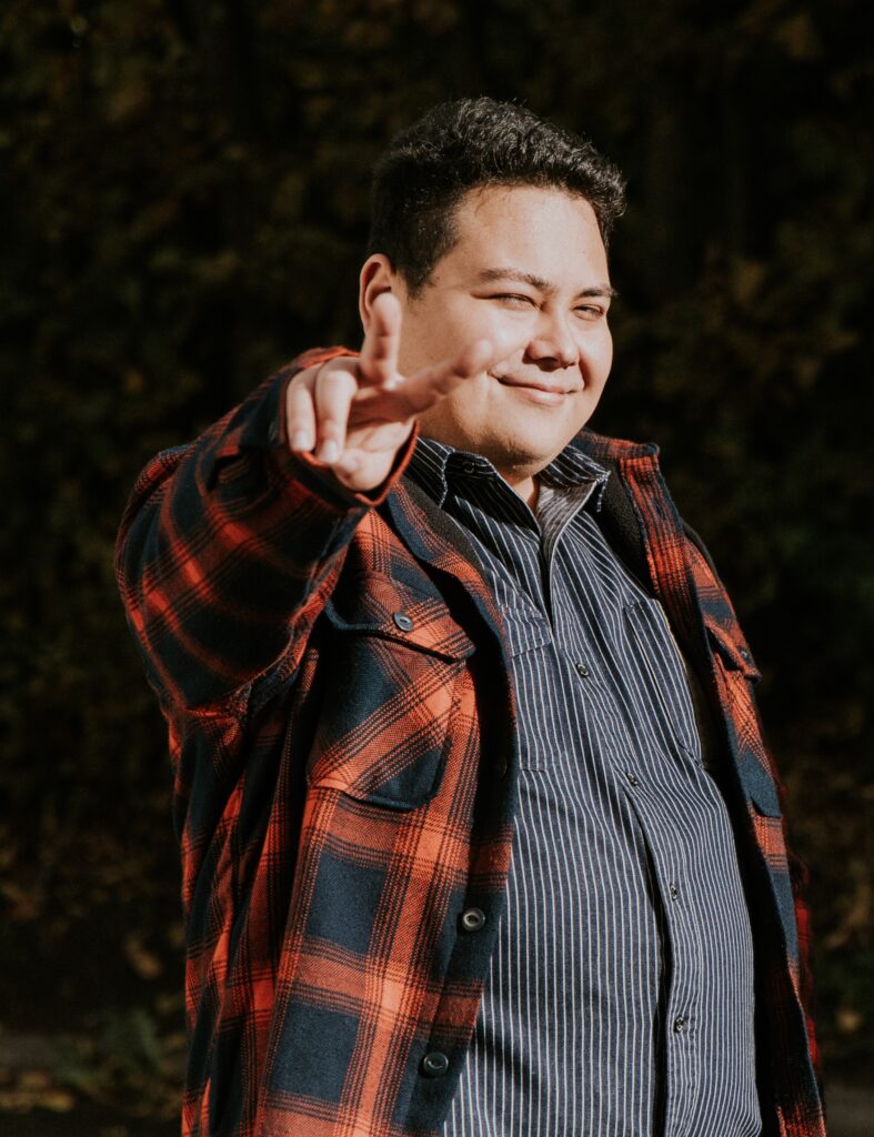 Junge Mann in Jacke winkt in der Natur.
