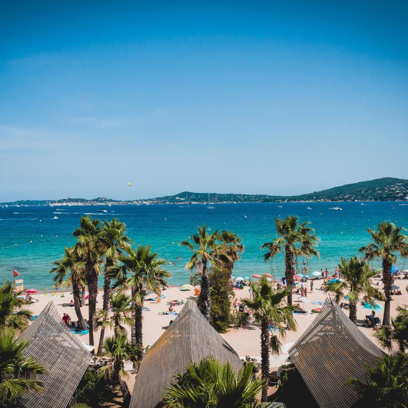 Entspannter Strand mit Palmen, Sonnenliegen und Blick auf das blaue Meer, ideal für Sommerferien und Erholung während des Herbstcamps.