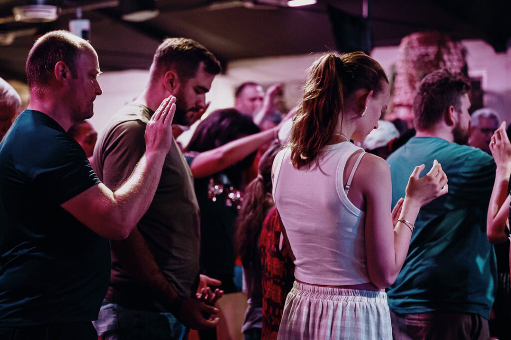 Menschen beim Gebet in der ICF Basel-Land Gemeinde, betend und in Gemeinschaft, bei einer religiösen Veranstaltung.