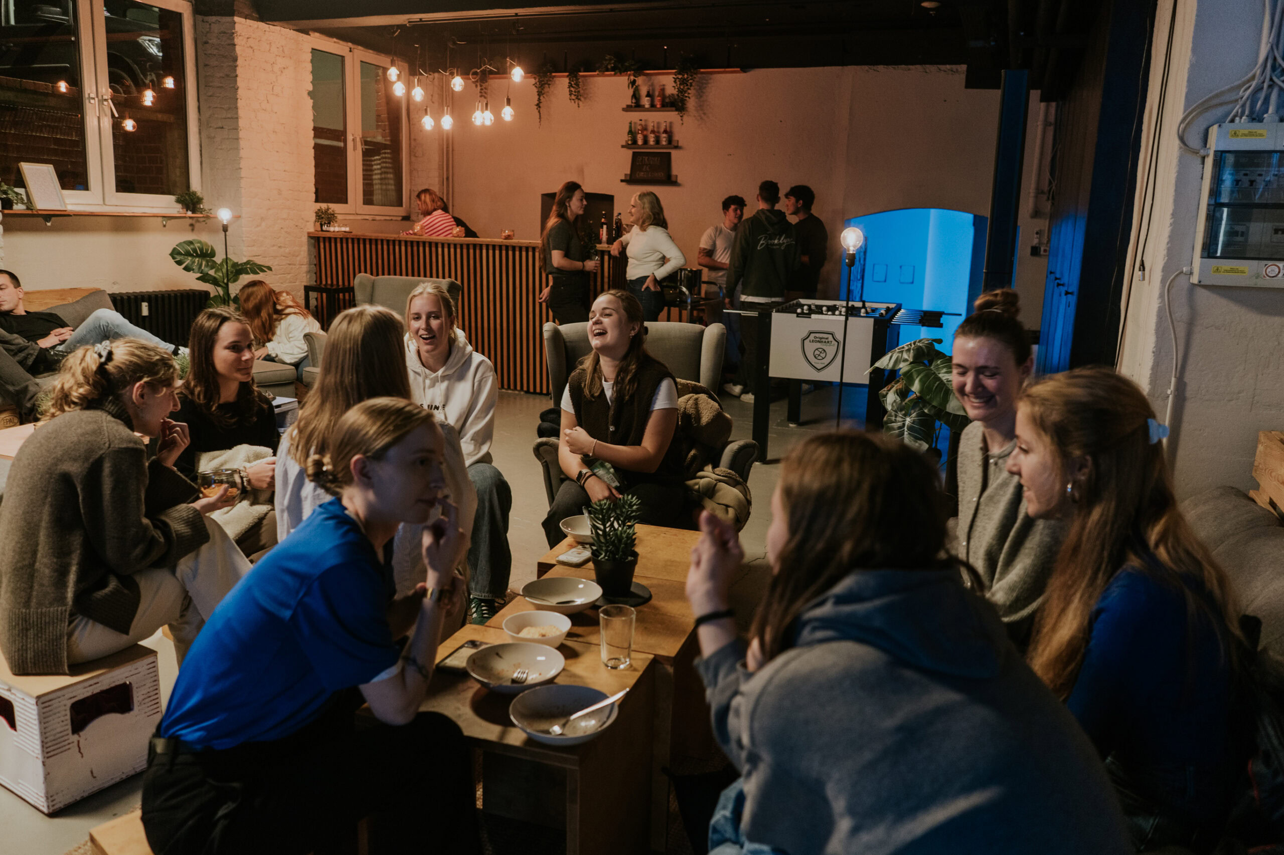 Friends and church members gathering in a cozy room for a social evening at ICF Berlin, laughing and chatting.