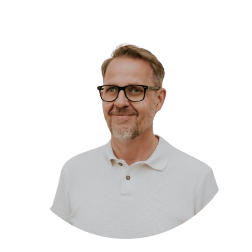 Portrait eines Mannes mit Brille, lächelnd, in weißem Polo, symbolisiert Führung und Gemeinschaft bei ICF Berlin.