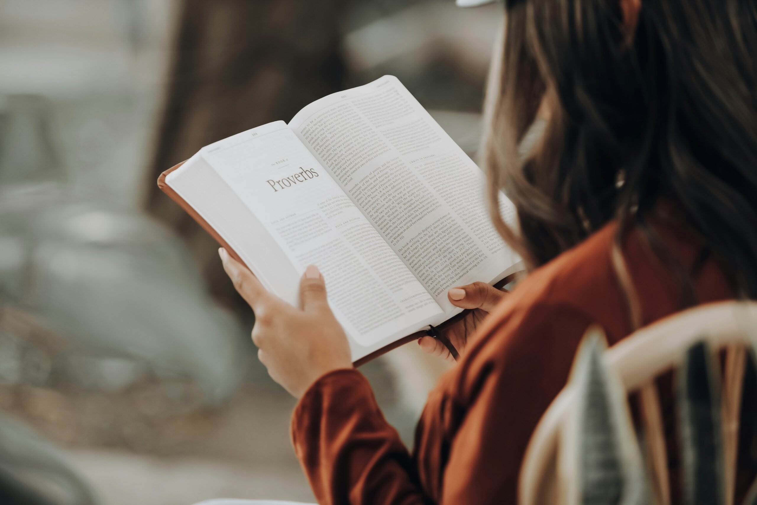 Frau liest in einem Gottesdienst in Berlin die Bibel, umgeben von Natur, mit Fokus auf christliche Gemeinschaft und Glauben.