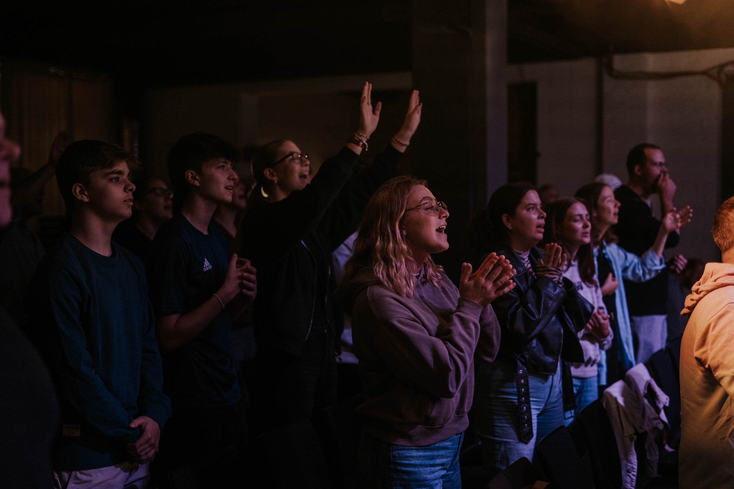 Jugendliche und Erwachsene beim Gottesdienst in Berlin, die aktiv an der Kirche teilnehmen und beten.