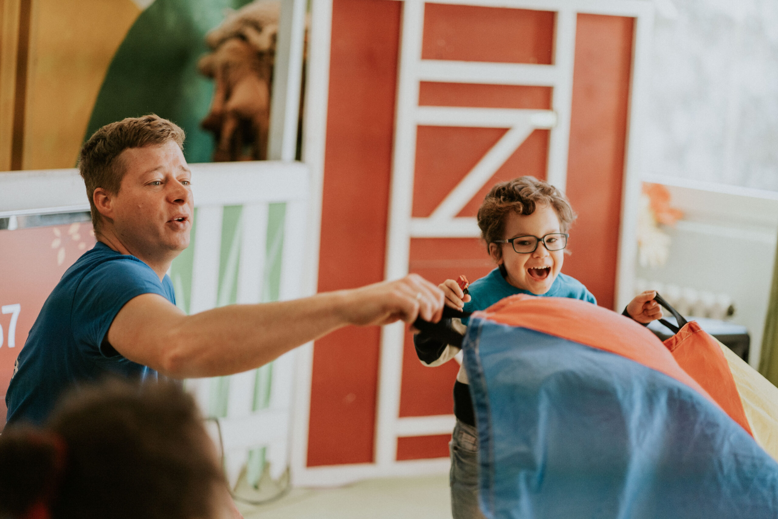 Two children are playing with a colorful air mattress in a room.