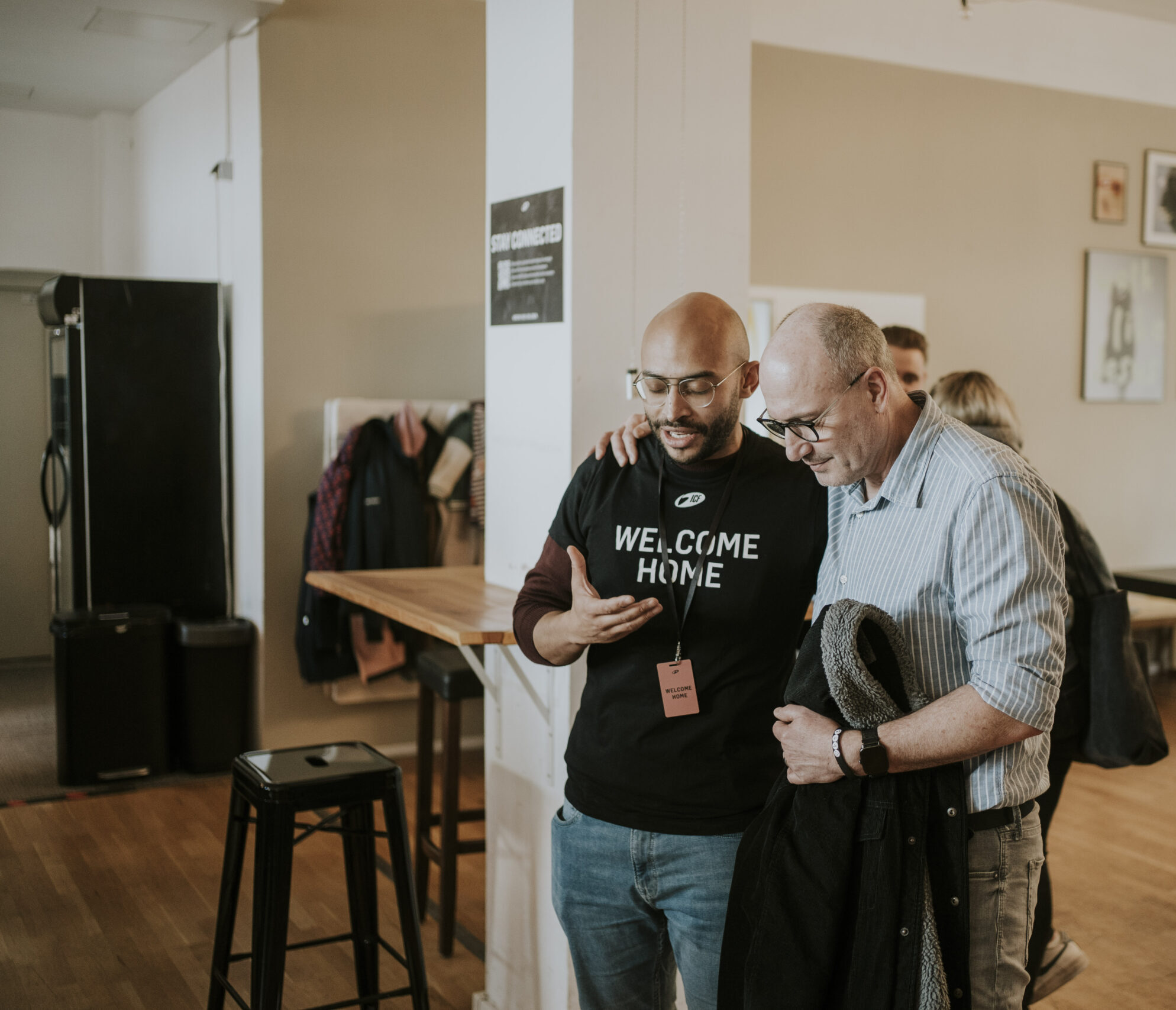 Two men are standing in a room, laughing and talking.