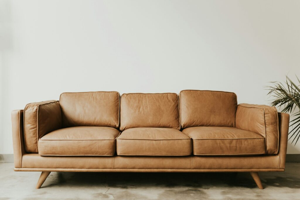 Braunes Schlafsofa mit drei Sitzkissen vor weißer Wand.