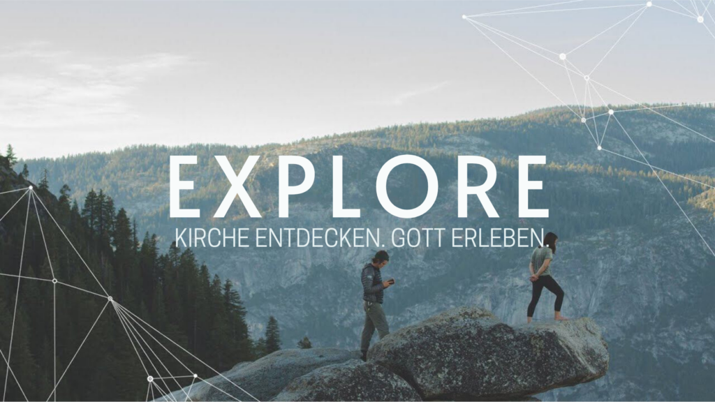 Zwei Personen stehen auf einem großen Felsen in einer Bergregion, umgeben von Wäldern und Bergen im.
