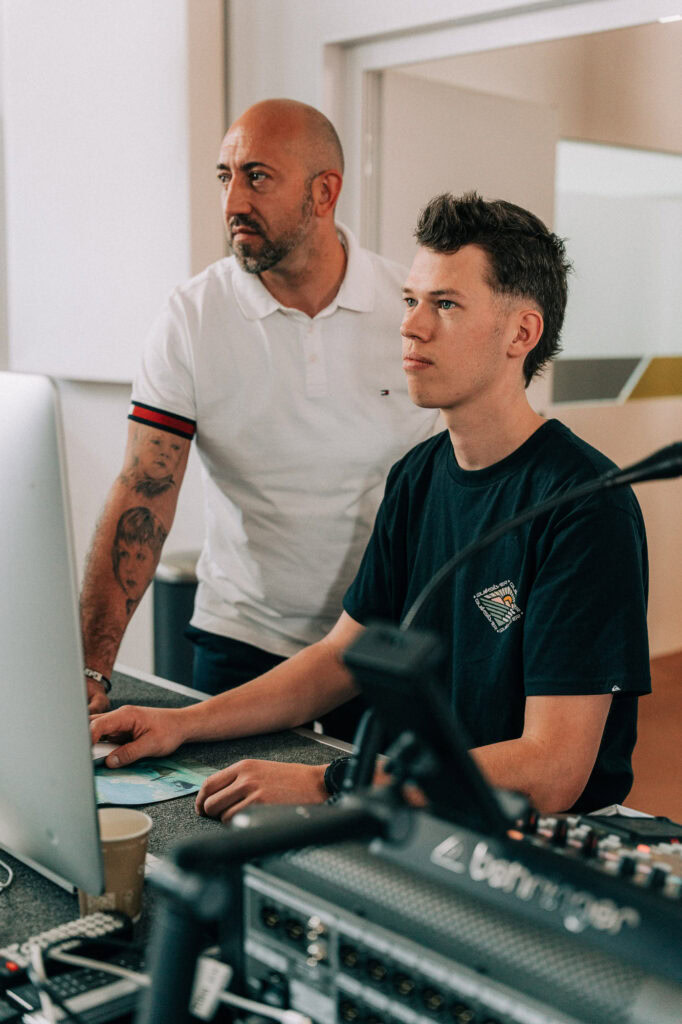 Zwei Männer arbeiten an einem Computer im Tonstudio.