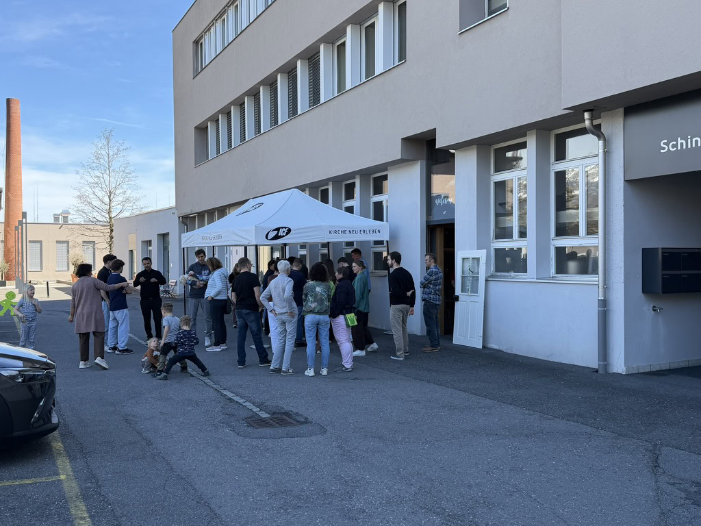 Menschen stehen in einer Reihe vor einem Pavillon vor einem weißen Gebäude.