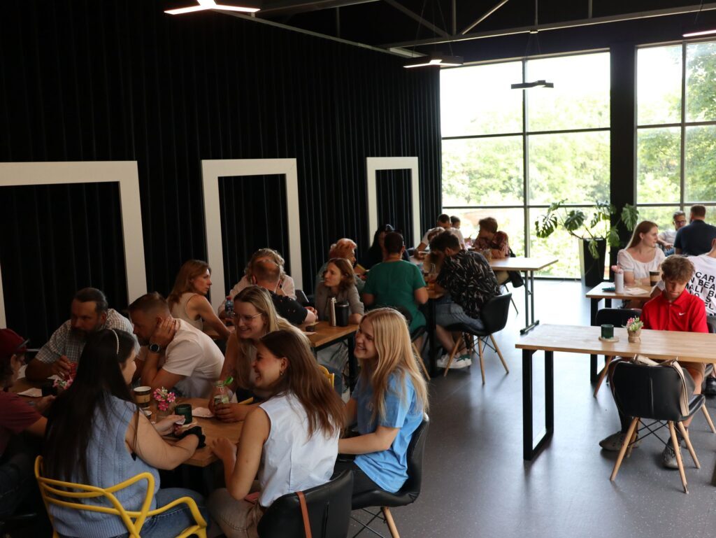 A group of people sitting at tables in a coffee shop, engaging in conversations.