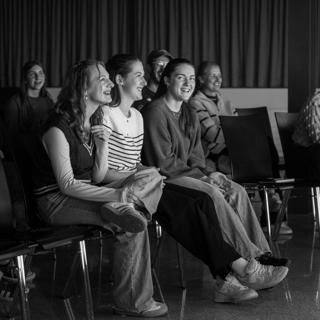 Frauen lachen und freuen sich im Publikum bei einem Vortrag.