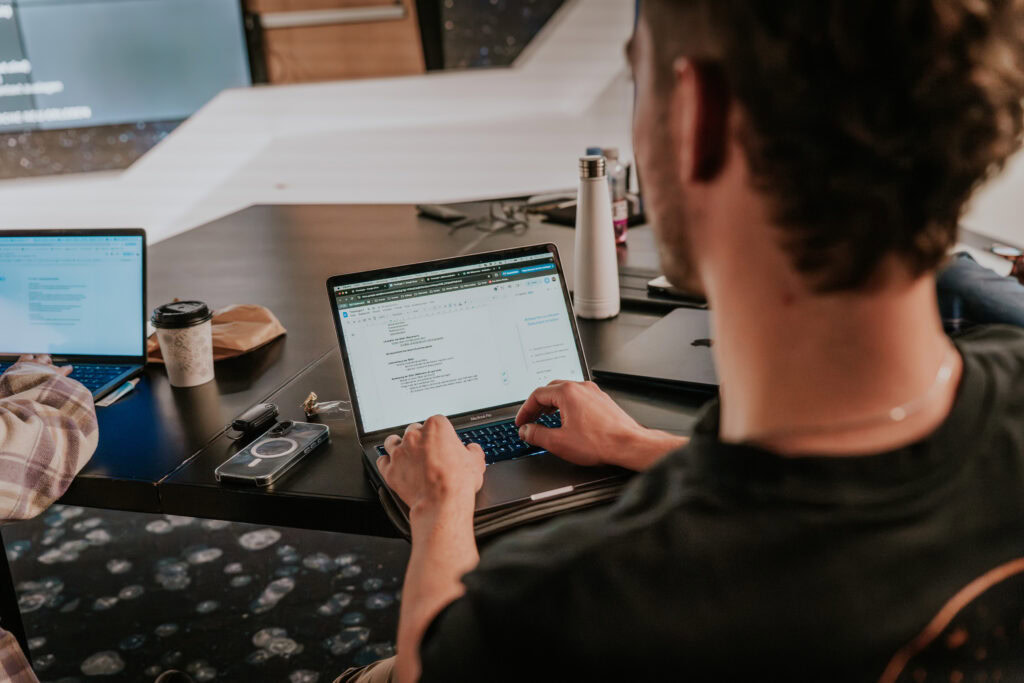 Mann arbeitet an einem Laptop in einem Co-Working-Büro, Blick auf den Bildschirm.