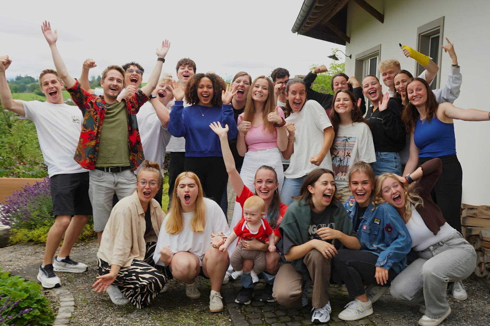 Gruppe von Menschen, die draußen vor einem Haus lachen und feiern.