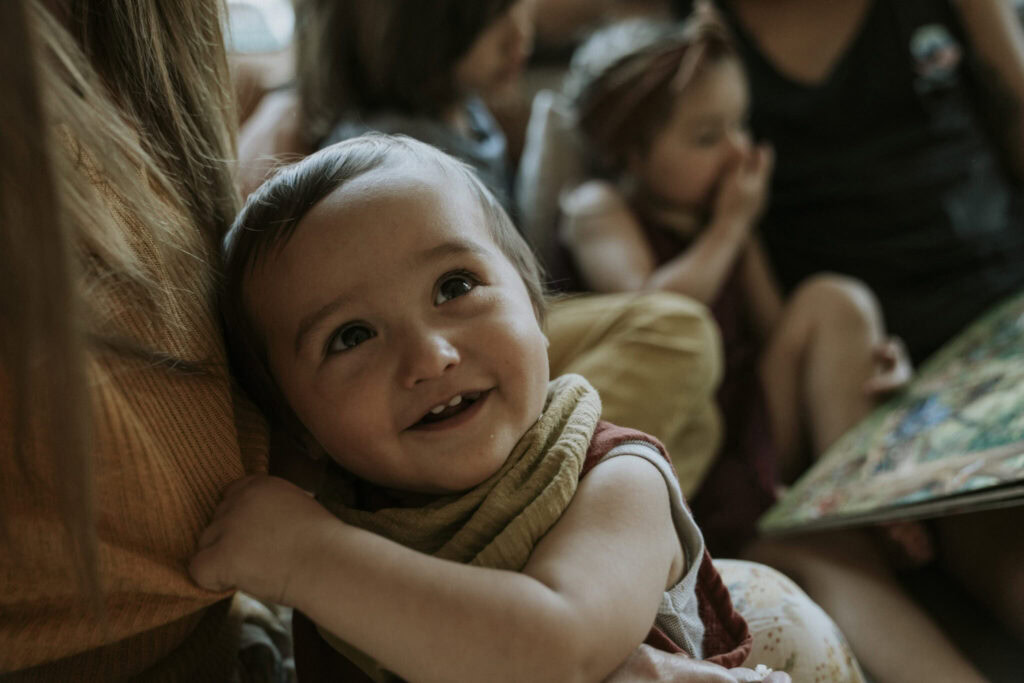 Junge Kinder hören aufmerksam einer Frau beim Vorlesen zu.