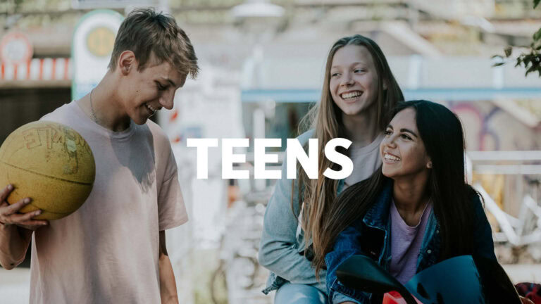 Drei Teenager, zwei Mädchen und ein Junge, lachen und unterhalten sich, während der Junge einen Bask.