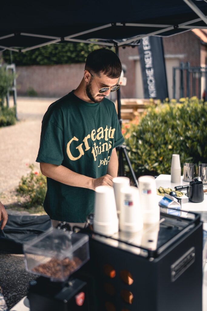 Ein Mann bereitet Kaffee bei einem Outdoor-Event der Gemeinde ICF in Essen. Mit Fokus auf Gemeinschaft, Glauben und Integration, verbindet die Kirche Menschen beim Treffen im Freien.