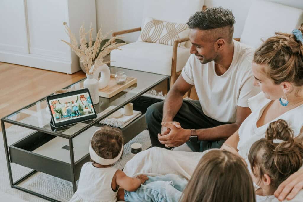 Familie schaut gemeinsam ein virtuelles Weihnachtsvideo via Tablet, gemütlich im Wohnzimmer, kreative digitale Familienzeit, romantische Weihnachtsstimmung, festliche Atmosphäre, moderne Familienfeier, gemeinsames Online-Erlebnis, Weihnachtsaktion, virtuelle Festtage, Familienbindung.