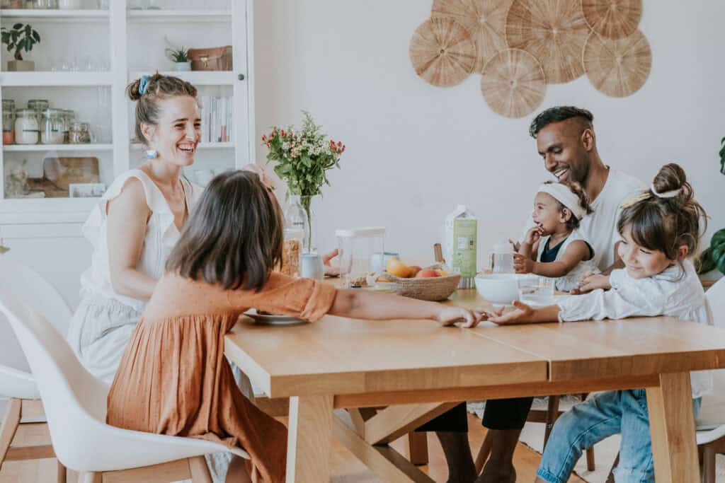 Freundliche Familie beim gemeinsamen Frühstück in modernem Esszimmer, glückliche Eltern mit Kindern, natürliche Lichtstimmung, harmonische Atmosphäre für Familienleben und Zusammengehörigkeit, Lifestyle, Familienzeit, Zuhause, Möbel, Esszimmerdekoration, moderne Einrichtung, nachhaltiges Wohnen, Indoor-Familienaktivitäten, kreative Familienzeit, Wohnideen, skandinavisches Design, Familienalltag, Kinderfreundliches Zuhause, Lifestyle-Fotografie, positive Familienmomente.