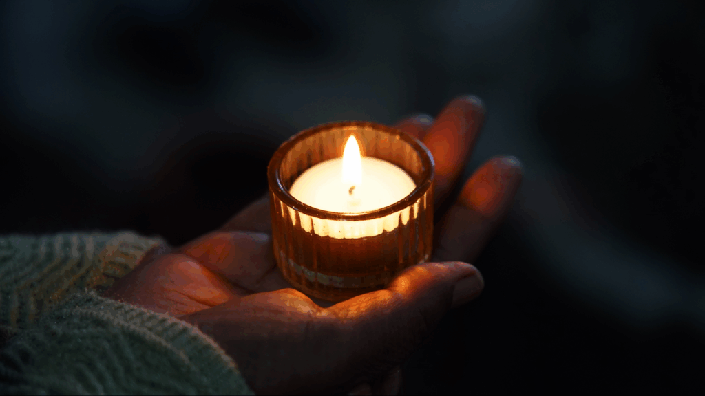 Kerze in einer Hand, symbolisiert Hoffnung und spirituelle Wärme, ideal für christliche Gemeinschafts- und Glaubensveranstaltungen in Fribourg, ICF Kirche, Fokus auf Gebet und Gemeinschaft.