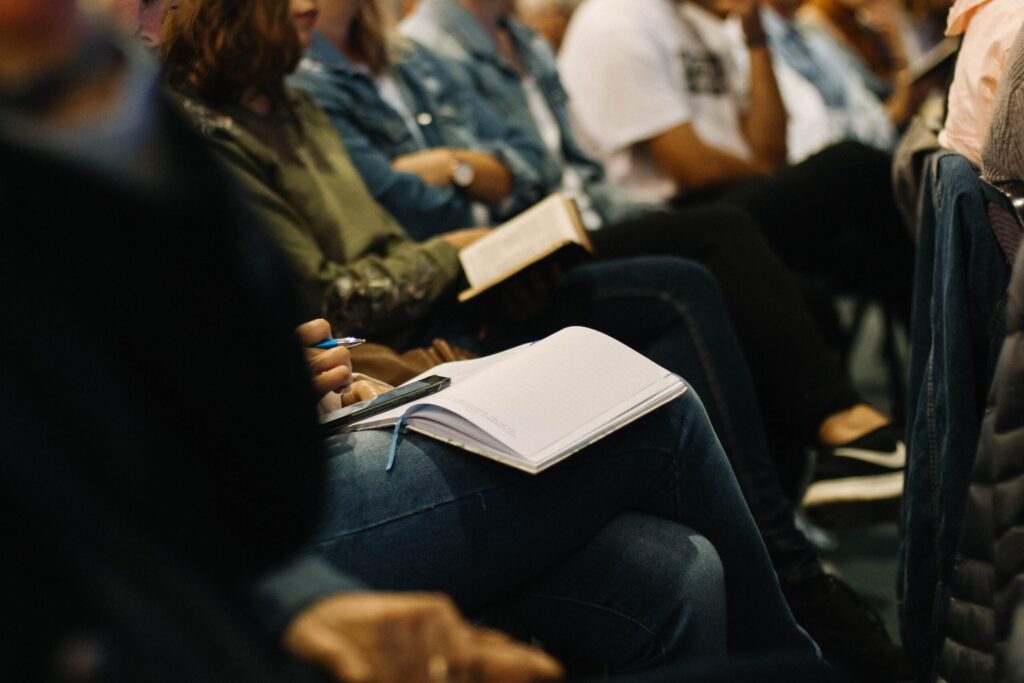 Audience members sitting with notebooks and pens.