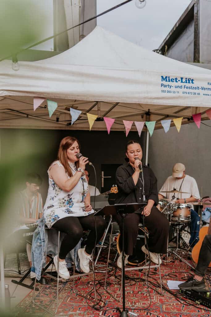 Fröhliche Live-Musik bei einem Event im Freien mit Band, bunten Dekorationen und Publikum, ideal für Veranstaltungsorte, Musikliebhaber und kulturelle Events in Deutschland.