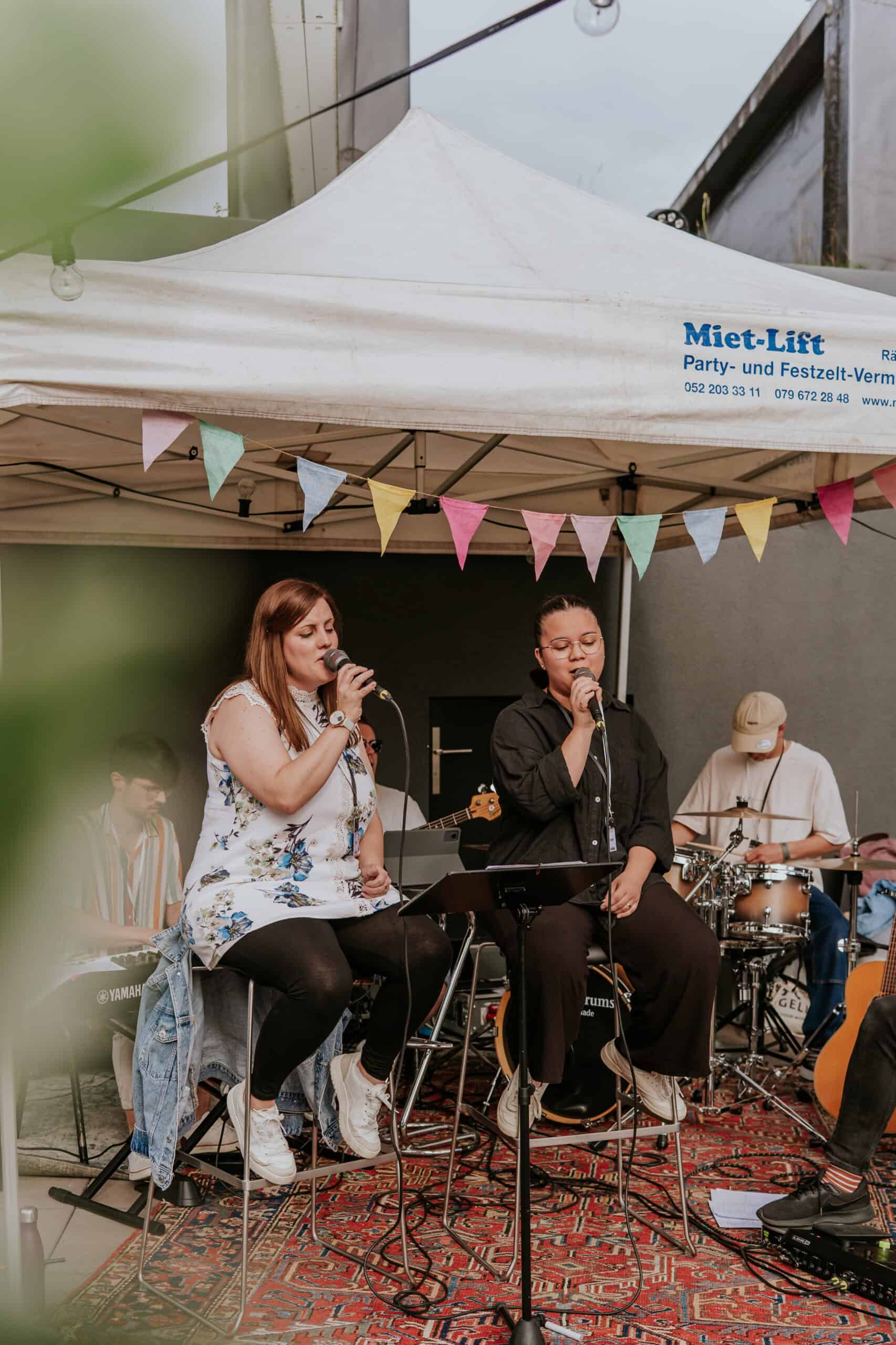 Fröhliche Live-Musik bei einem Event im Freien mit Band, bunten Dekorationen und Publikum, ideal für Veranstaltungsorte, Musikliebhaber und kulturelle Events in Deutschland.