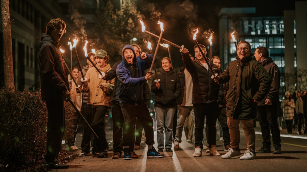 Gruppe von Menschen, die mit Fackeln jonglieren, bei Nacht im Freien.