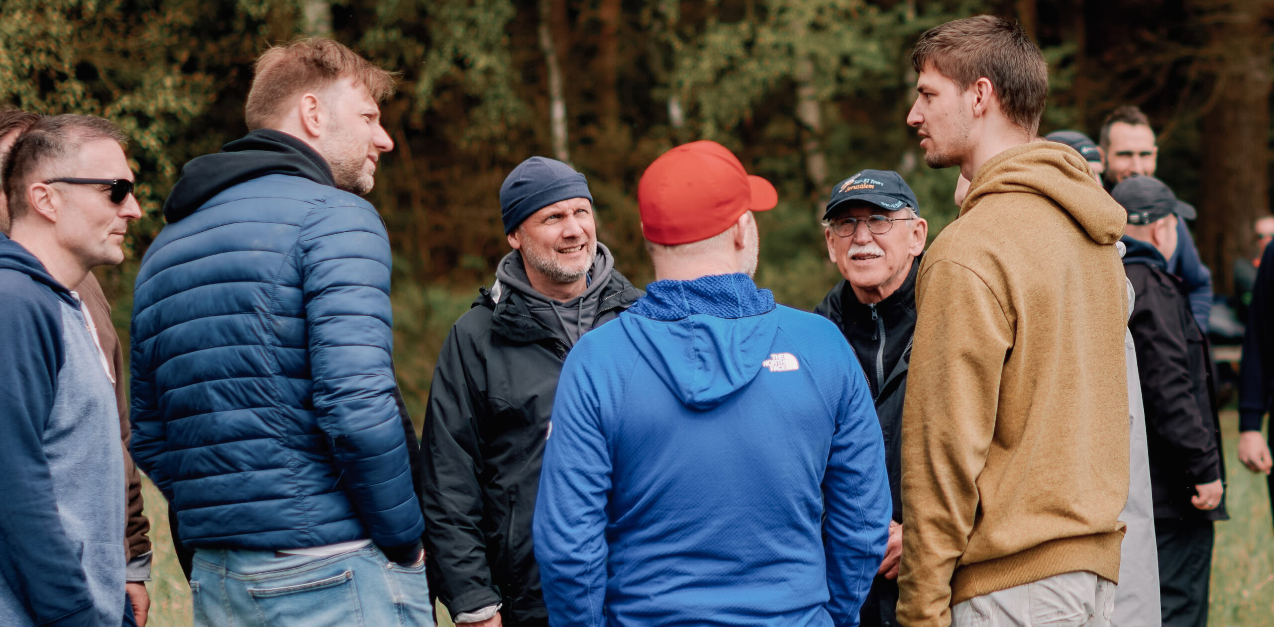 Gruppe von Menschen im Gespräch im Freien bei ICF Hamburg, Gemeinschaft und Austausch, junge Erwachsene, Natur, freundliche Atmosphäre.