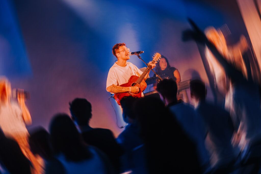 Musiker beim Lobpreis- und Gebetsabend in der ICF Hamburg Kirche, mit Gitarre und Mikrofon, umgeben von einer begeisterten Gemeinde.