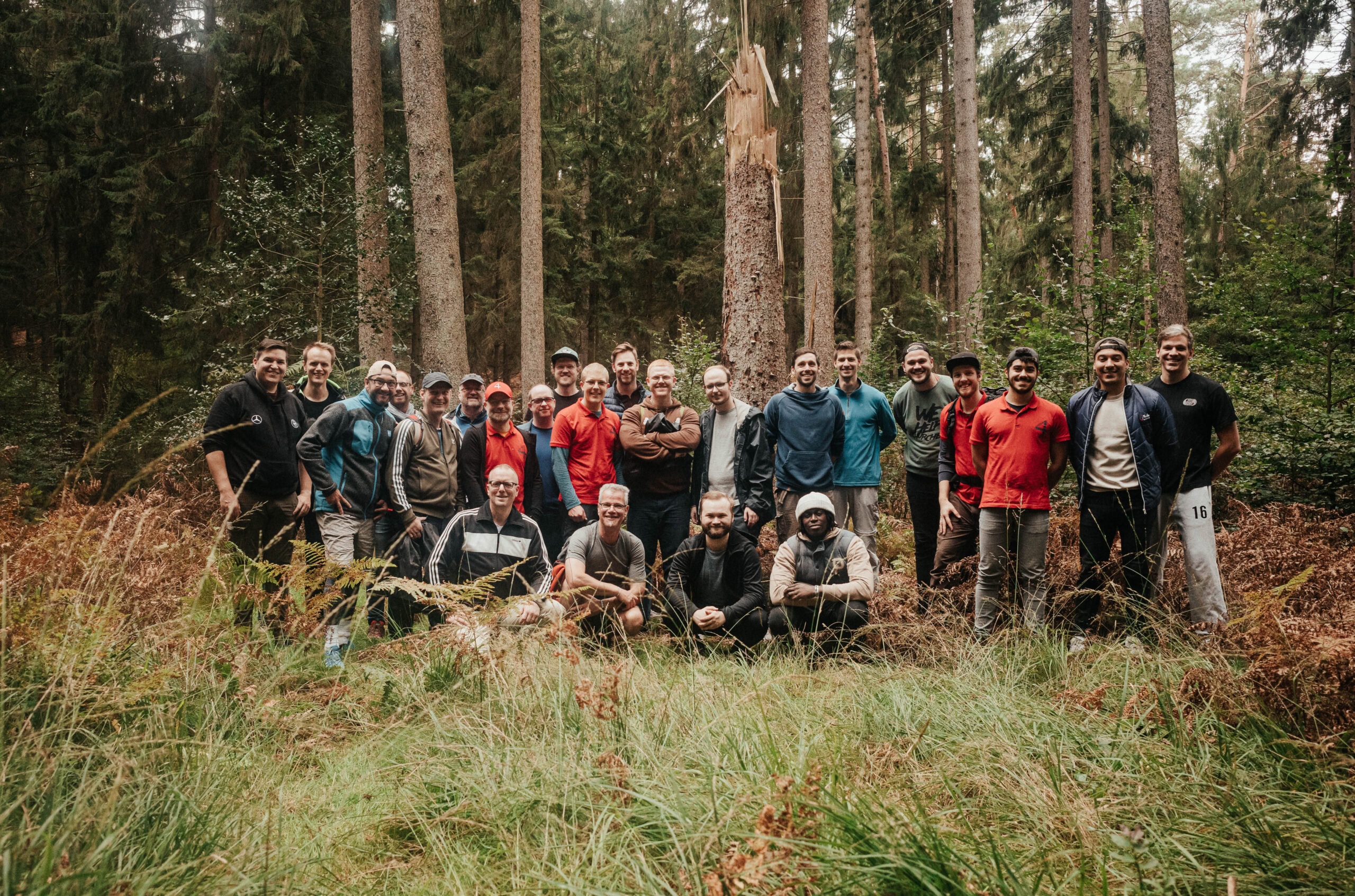 Gruppe von Menschen steht im Wald vor Bäumen.