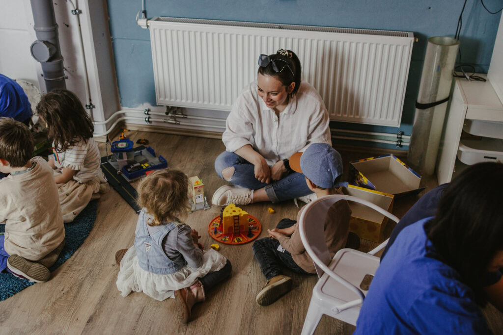 Fröhliche Kinder spielen während der Kinderbetreuung bei einer kirchlichen Veranstaltung in Herrenberg, mit einer lachenden Betreuerin, kreativem Spielzeug und gemeinsamer Freude im Kirchenraum.
