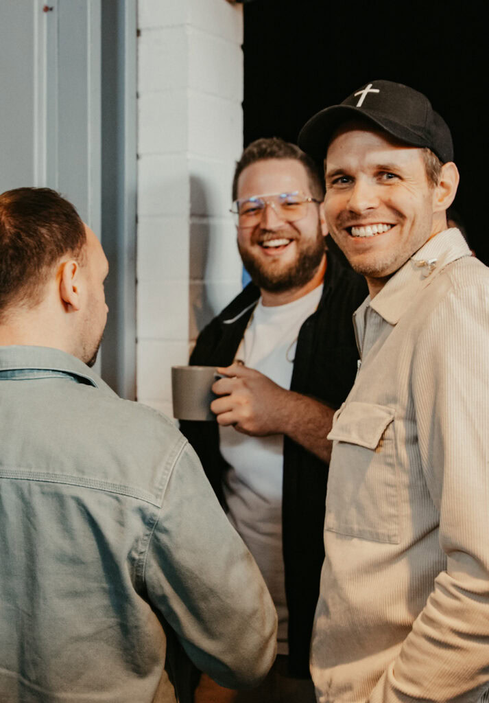 Menschen stehen in einer Gruppe, lachen und unterhalten sich.