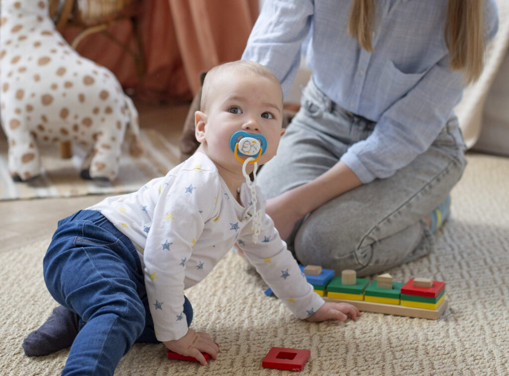 Eine Frau und ein Baby spielen auf einem Teppich.