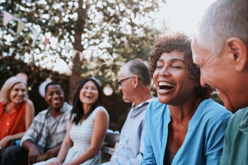Menschen sitzen im garten, lachen und unterhalten sich.