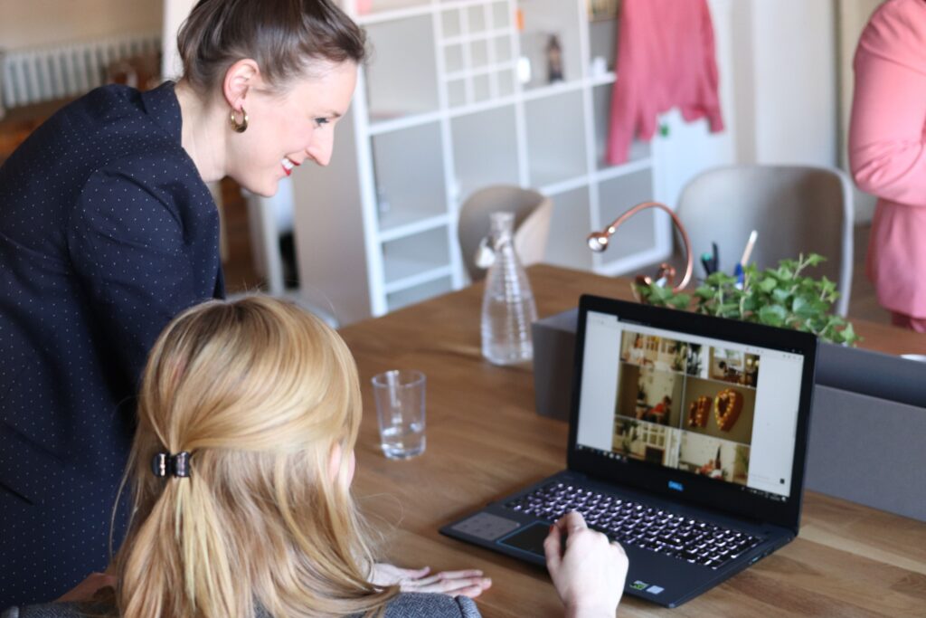 Frau und Kind schauen auf einen Laptop auf einem Tisch.