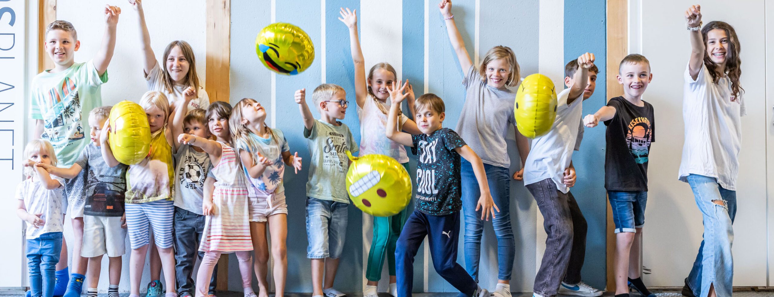 Kinder spielen mit gelben Bällen in der Turnhalle.