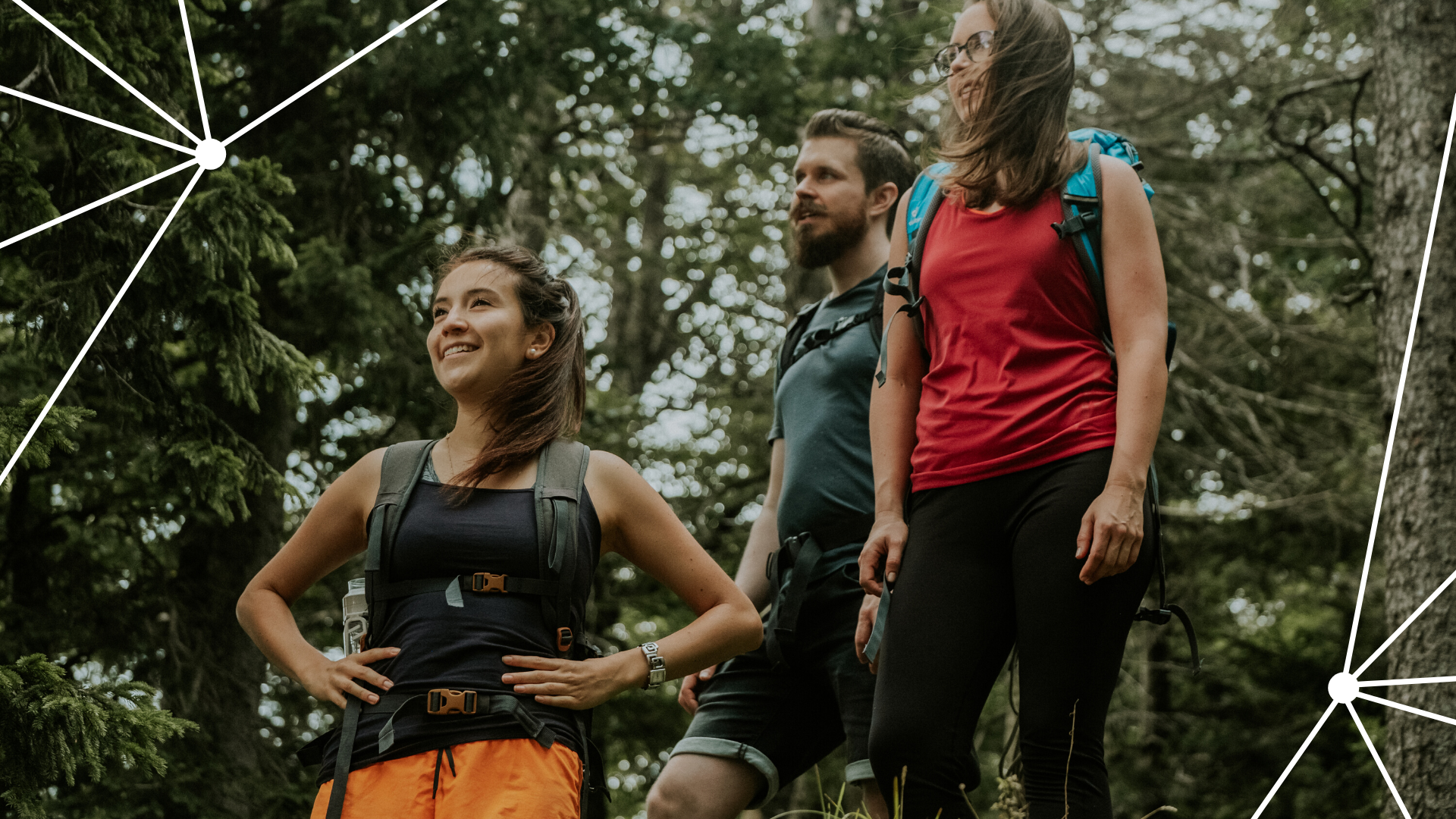 Drei Wanderer im Wald, zwei Frauen und ein Mann, mit Rucksäcken.
