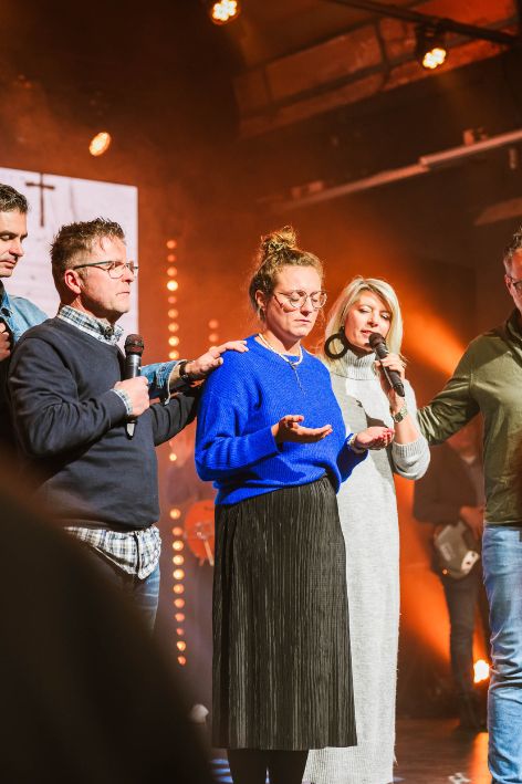 Menschen beten und singen während eines Gemeindegottesdienstes in Karlsruhe, mit warmem Licht und moderner Atmosphäre.
