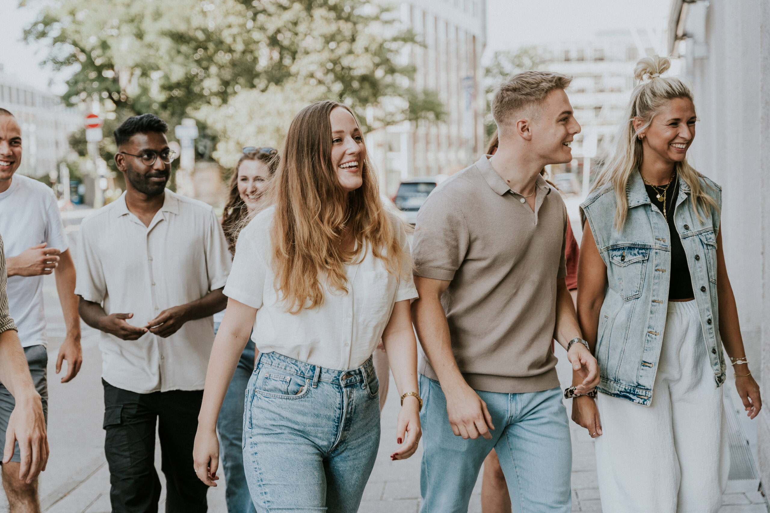 Mehrere junge Menschen gehen zusammen auf der Straße, lachen und unterhalten sich.