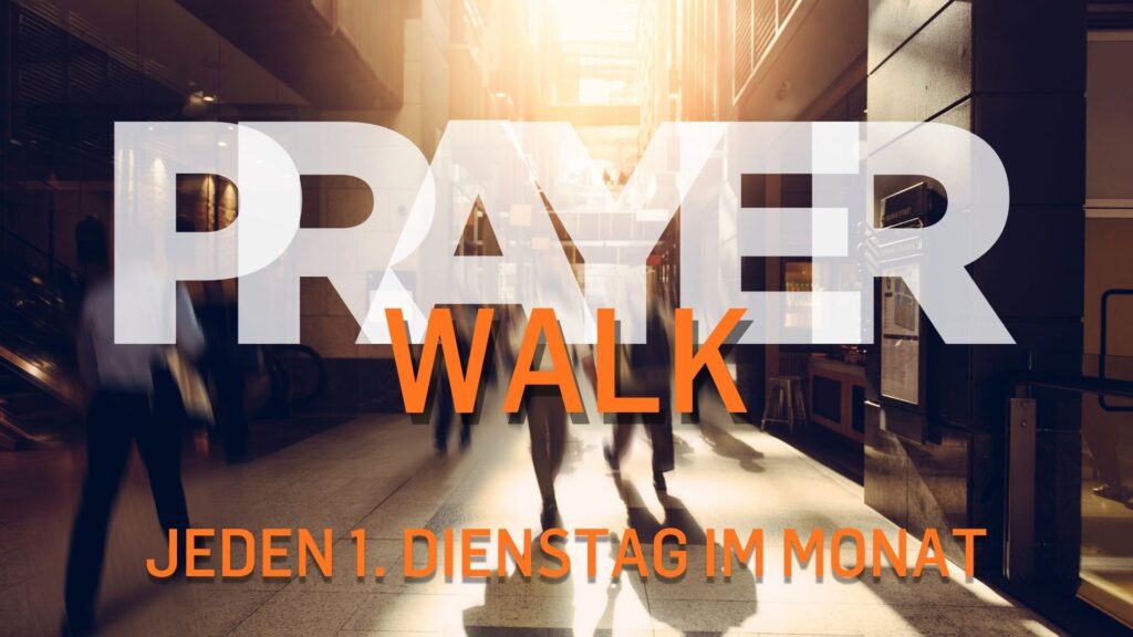Menschen gehen durch eine belebte Stadtstraße bei Sonnenlicht.