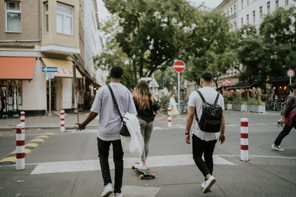 Bewegte Stadtszene mit jungen Leuten, die die Kreuzung überqueren, Skaten und unterwegs sind in einer urbanen Umgebung in Deutschland.
