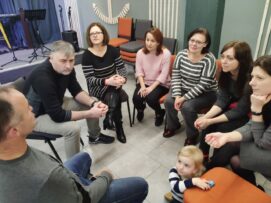Люди, що сидять у колі, спілкуються у кімнаті.