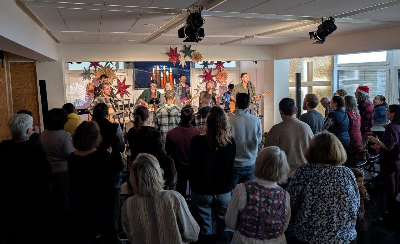 Musiciens jouant en live lors d'une fête de Noël, avec décorations festives en arrière-plan.