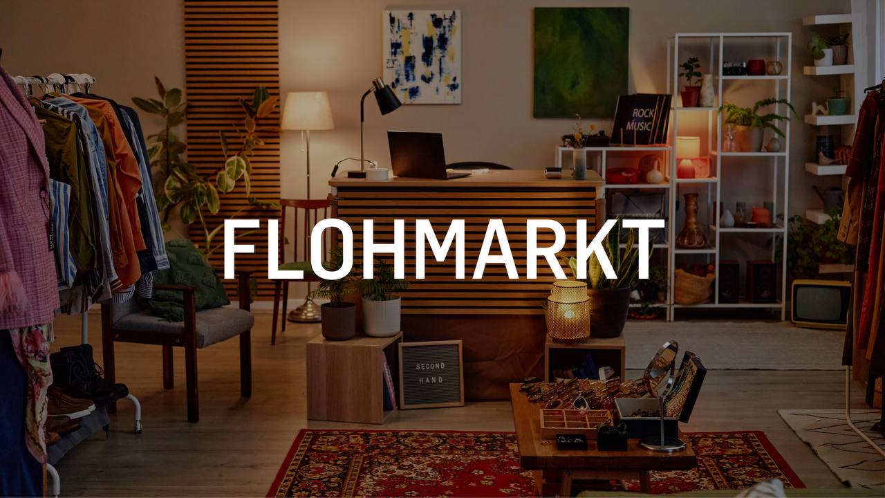 Innenraum eines Flohmarkts mit Kleidung, Möbeln und Dekorationsgegenständen.