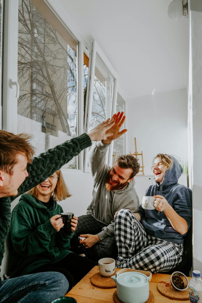 Quatro pessoas sentadas numa sala a conversar e a sorrir, com chá e comida na mesa.