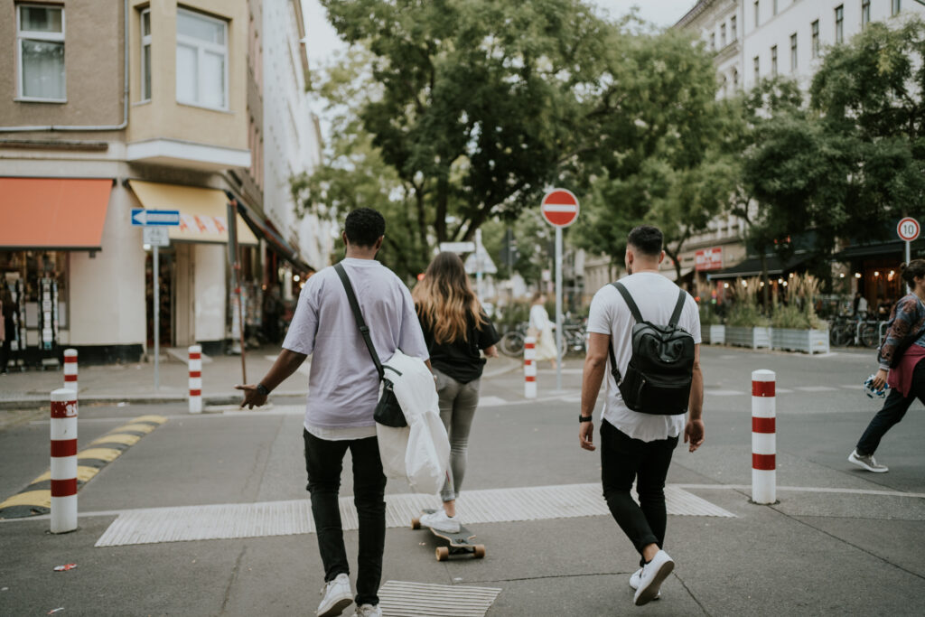 Bewegte Stadtszene mit jungen Leuten, die die Kreuzung überqueren, Skaten und unterwegs sind in einer urbanen Umgebung in Deutschland.