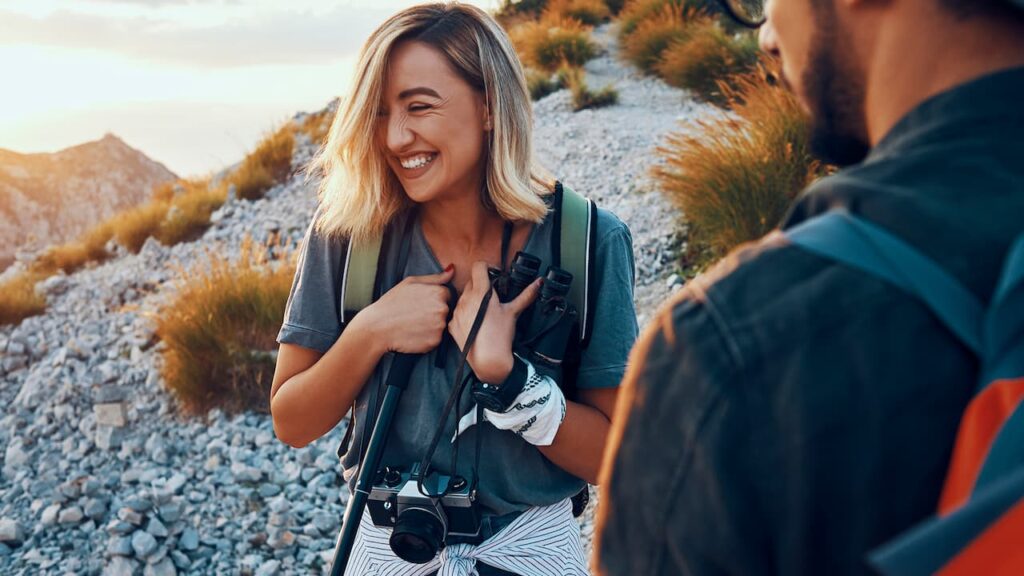 Frau mit Rucksack und Kamera beim Wandern im Gebirge.